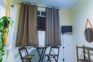 a room with chairs and a table and a window at Suite dos Anjos com Cozinha 150m da Praia in Arraial do Cabo