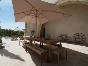 een patio met een tafel, banken en een parasol bij Holiday Home in Hérault with Pool in Campagnan