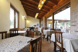 un ristorante con tavoli e sedie bianchi e finestre di Corte di Tosina a Monzambano