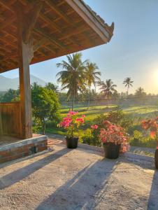 a porch of a house with flowers and palm trees at Nataqueen Bungalows in Tetebatu