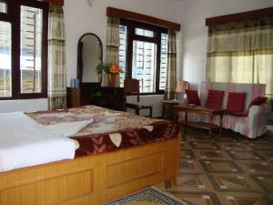 a bedroom with a bed and chairs and a mirror at New Summit Guest House in Pokhara
