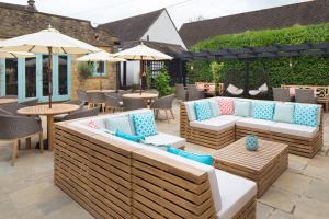 a patio with couches and tables and umbrellas at The Sheep on Sheep Street Hotel in Stow on the Wold
