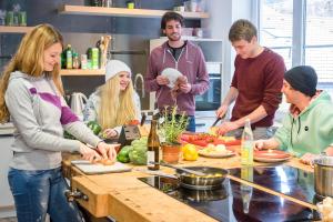 a group of people in a kitchen preparing food at Oberstdorf Hostel in Oberstdorf