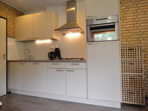 Una cocina con gabinetes blancos y una estufa. en Pet-Friendly Getaway, en Stramproy