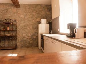 a kitchen with a white refrigerator and a stone wall at Holiday Home in Montbrun with Pool & Vineyards in Montbrun-des-Corbières