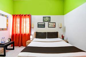 1 dormitorio con 1 cama con paredes de color verde y rojo en Hotel O Modern Stay Near ITER, en Bhubaneshwar