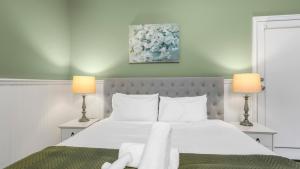 une chambre avec un grand lit blanc avec deux lampes dans l'établissement Little Plum Cottage, à Apollo Bay