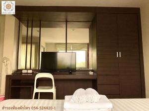 a room with a tv and a chair and a table at Huern Che Ta One Hotel in Phrae