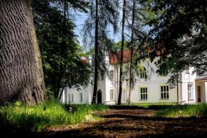a white house with trees in front of it at Altana Kasztelana - Domek Letniskowy z tarasem i jacuzzi nad Dunajcem Velo in Wojnicz