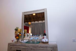Una mesa con vasos y una botella de vino frente a un espejo. en Akagera Safari Camp, en Kigali 10 fotos más