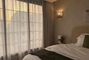 a bedroom with a bed and a large window at Malath - The Bohemian Haven in Dammam