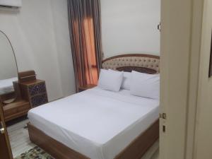 a bedroom with a bed with white sheets and pillows at شقه فندقيه in Sheikh Zayed