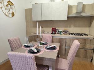 a dining room table with pink chairs and a kitchen at La perla di Caserta 2 in Caserta +15 photos