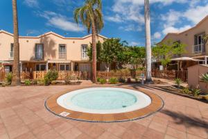 a swimming pool in front of a house with palm trees at Maspalomas Green Oasis in San Bartolomé de Tirajana