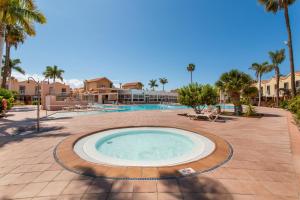 a large swimming pool in a courtyard with palm trees at Maspalomas Green Oasis in San Bartolomé de Tirajana