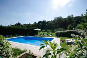 a swimming pool in a yard with chairs and an umbrella at Agriturismo Val in Costermano
