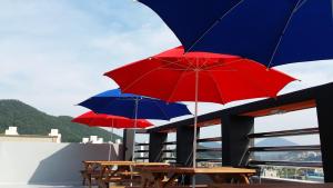 trzy stoły z parasolami na dachu budynku w obiekcie Suzy Pension w mieście Yeosu