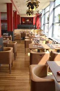 a dining room with tables and chairs and windows at Le Grand Hotel in Maubeuge