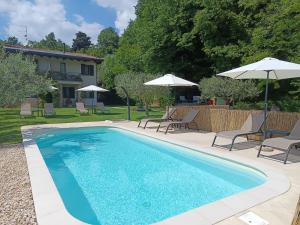 a swimming pool with chairs and umbrellas next to a house at B&B Al Sentiero in Caprino Veronese