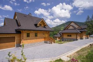 ein Haus mit einer großen Einfahrt davor in der Unterkunft Mosorny Park Drewniane Komfortowe Domki Całoroczne in Zawoja