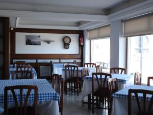 a restaurant with tables and chairs and a clock on the wall at Hotel Siroco Portonovo in Sanxenxo