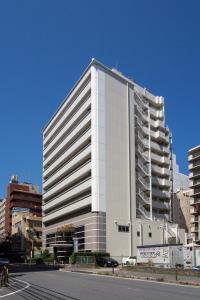 a tall white building on the side of a street at Hotel Claiton Esaka in Suita