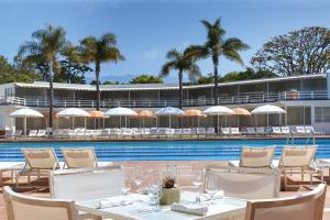 a pool with tables and chairs next to a resort at Four Seasons Resort The Biltmore Santa Barbara in Santa Barbara