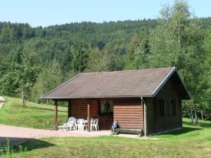 a log cabin with tables and chairs in a field at Ventron Chalet with Hill Views in Ventron +33 photos