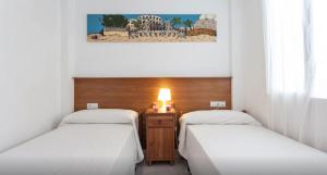 カディスにあるAtico Cadizのベッド2台とランプが備わる部屋