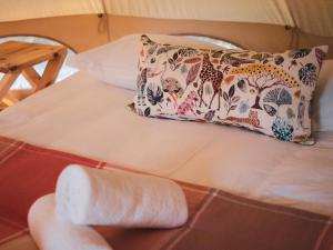 a bed with a pillow and a towel at The Leadwood Safari Camp in Dinokeng Game Reserve