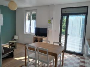 a living room with a table and chairs and a television at Maison de pêcheurs in Ault