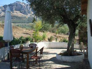 une table et des chaises avec un arbre et un parasol dans l'établissement Posada Niña Margarita, à Priego de Córdoba