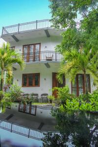 a house with a balcony and palm trees at River Pearl Villa in Seeduwa