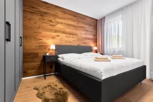 a bedroom with a large bed with a wooden wall at Apartmány Krušec by Mountain ways in Plešivec