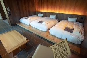 two beds in a room with a table and chairs at Nature Base Hotel NUPPUKOTTE in Teshikaga
