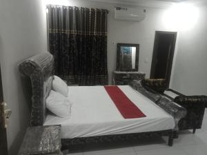 een slaapkamer met een bed met een rode streep erop bij Ryazm Guest house in Rawalpindi
