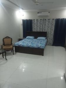 een slaapkamer met een bed en een stoel bij Ryazm Guest house in Rawalpindi