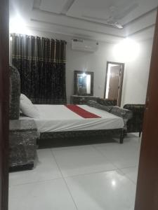 een slaapkamer met een bed en 2 stoelen. bij Ryazm Guest house in Rawalpindi