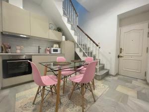 a dining room with pink chairs and a glass table at La Casa de María Castaña in Seville