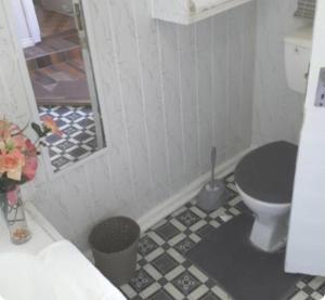 a bathroom with a toilet and a black and white tile floor at Richmond Hill Guesthouse- Serviced Condo in Gqeberha