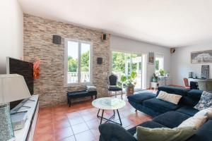 a living room with a blue couch and a brick wall at Maison Zoé- Haute pyrenees in Saint-Laurent-de-Neste