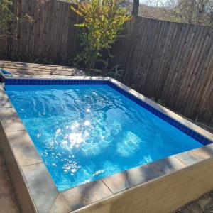 a swimming pool in a backyard with a wooden fence at Onse Boshuis in Marloth Park