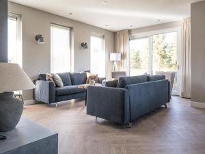 a living room with two blue couches and windows at Luxurious villa for 8 people in De Cocksdorp Texel in De Cocksdorp +10 photos