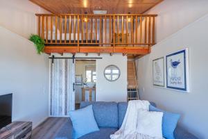 Una sala de estar con un sofá azul y un balcón. en Oceanview Tiny Home - Whitianga, en Whitianga