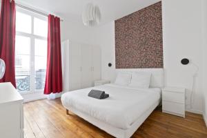 une chambre avec un lit blanc et un mur de briques dans l'établissement 2 Bedroom Apartment Île Saint-Louis With Free Netflix, à Paris