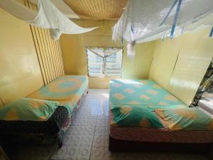 two beds in a small room with a window at Ruthy & Mali's homestay in Lautoka