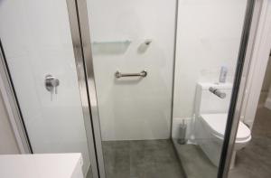 a bathroom with a toilet and a glass shower door at Seafield Tower Glenelg Apartment in Glenelg +63 photos