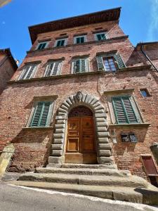 un edificio alto de ladrillo con puerta de madera en Residenza Neri-Serneri, en Foiano della Chiana