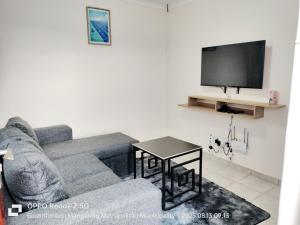 a living room with a couch and a tv at MV self-catering Linden in Bloemfontein