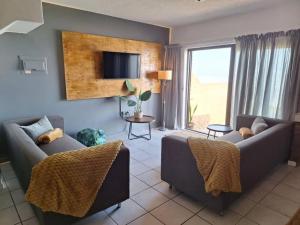 a living room with two couches and a tv at Beach Front 4 in Hentiesbaai